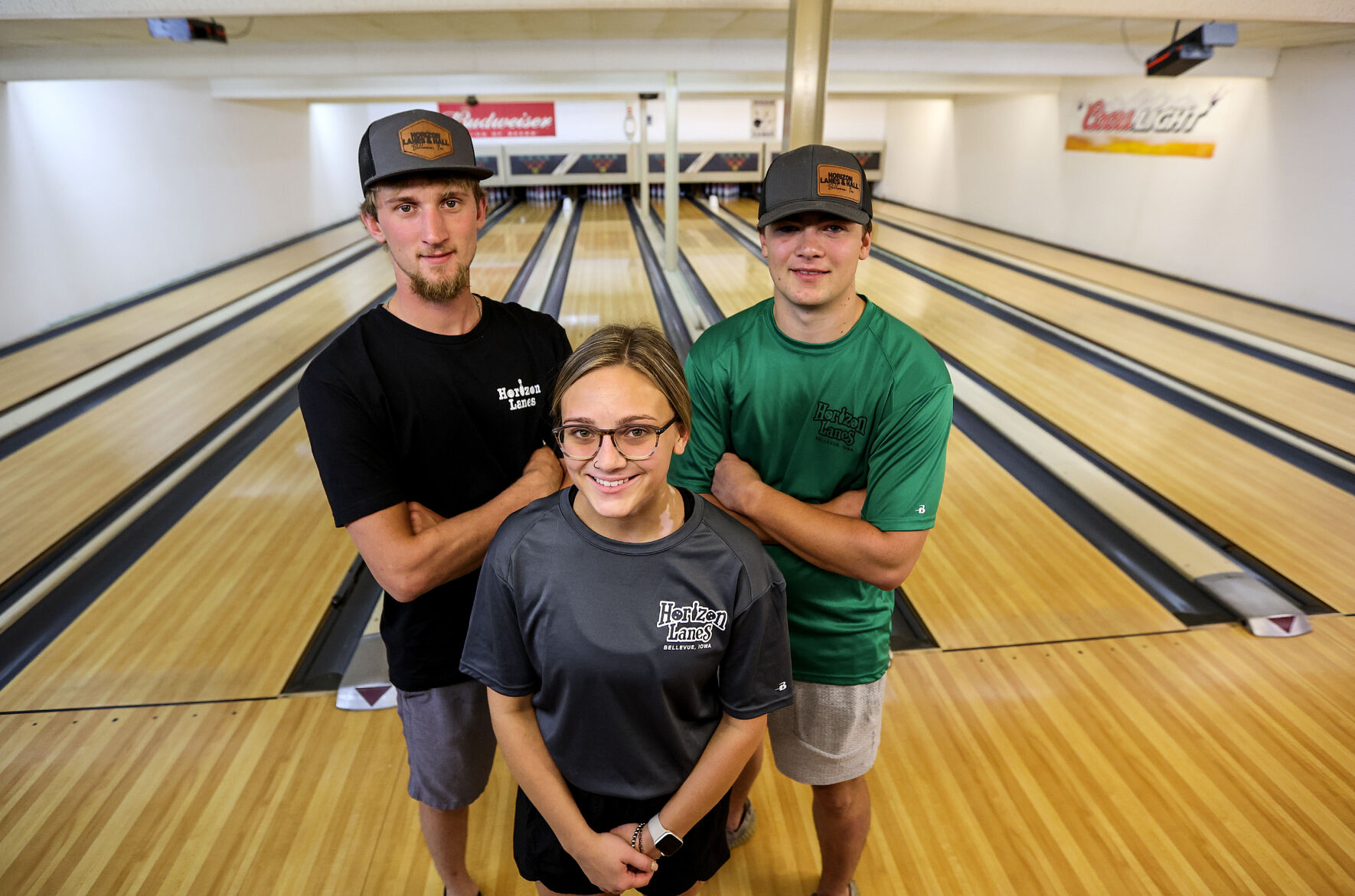 Co-owners of Horizon Lanes in Bellevue, Iowa, Dawson Weber (back left) and Trevor Hager (back right) stand with kitchen manager Madison Weber on Friday.    PHOTO CREDIT: Dave Kettering