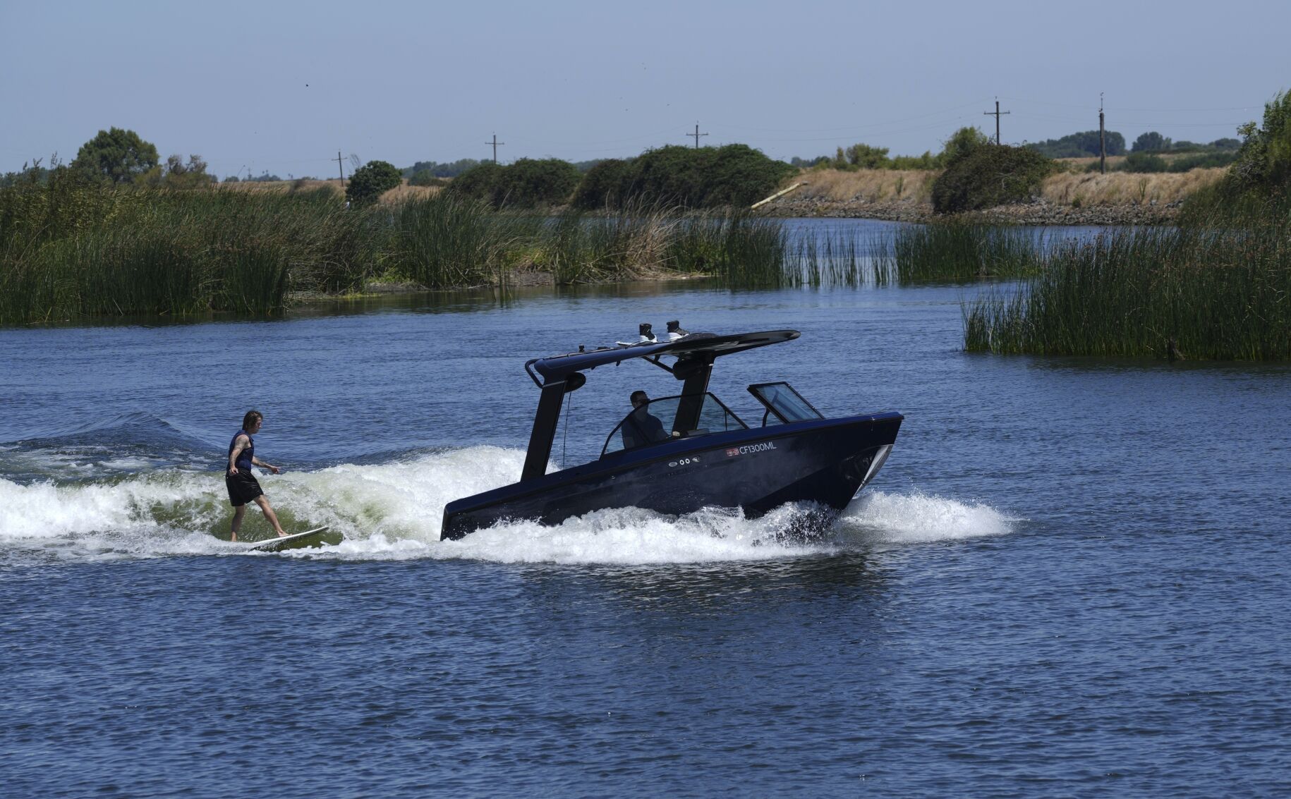 <p>Grant Jeide wake surfs behind an electric sports boat made by California-based Arc Boats on the Sacramento-San Joaquin Delta near Bethel Island, Calif. on Wednesday, July 31, 2024. (AP Photo/Terry Chea)</p>   PHOTO CREDIT: Terry Chea 