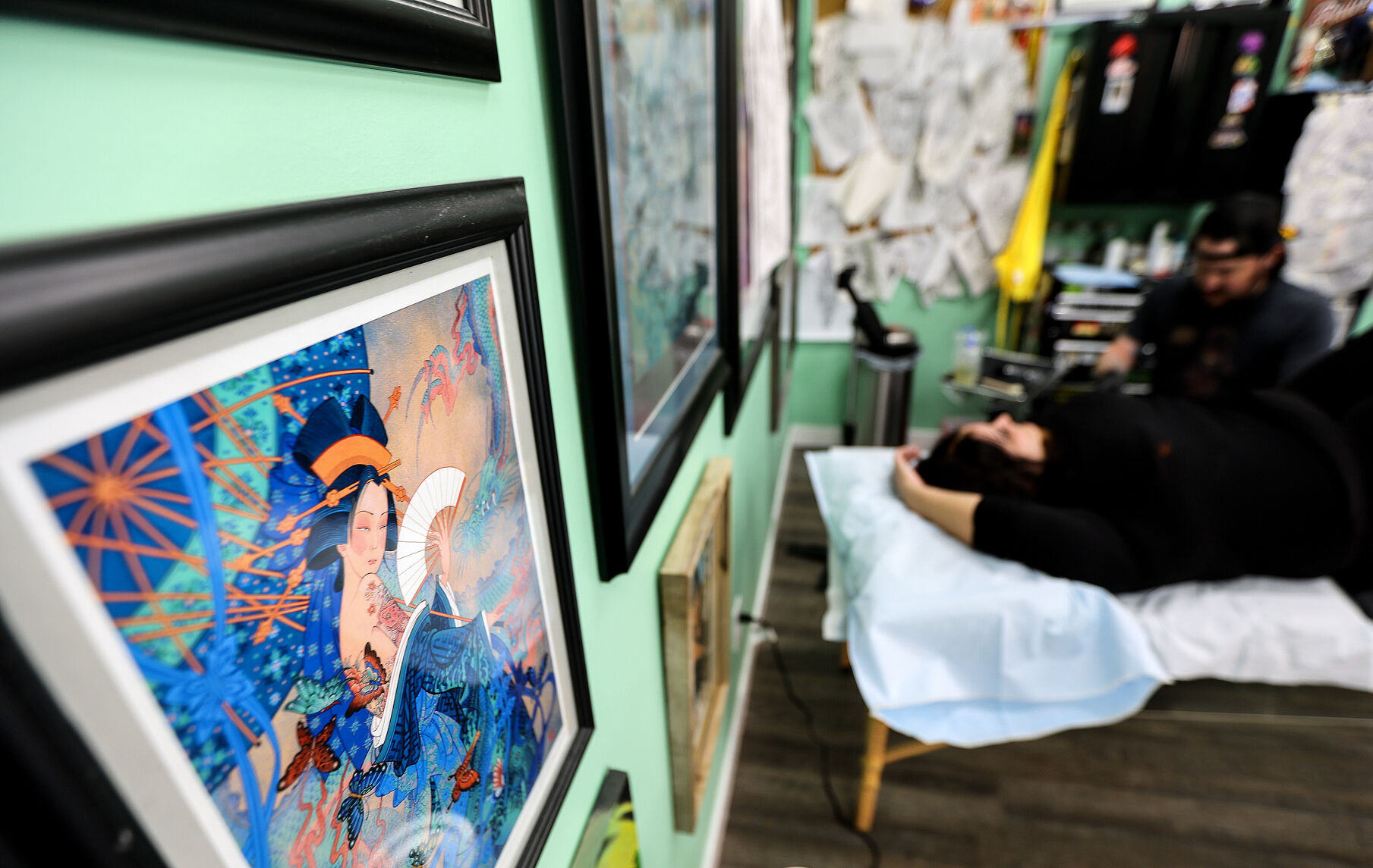 Alec Bauer works with a customer at First Light Tattoo & Gallery.    PHOTO CREDIT: Dave Kettering
Telegraph Herald