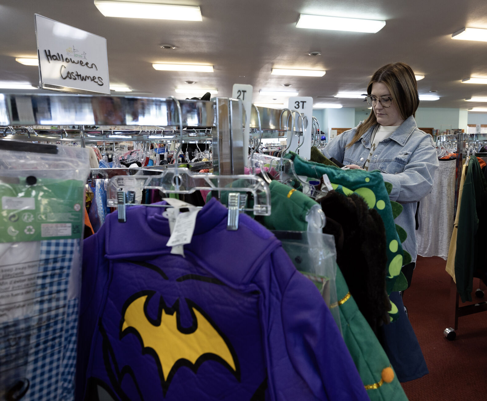 Assistant manager Courtney Gebke hangs up a Halloween costume at As They Grow in Dubuque on Tuesday.    PHOTO CREDIT: Gassman