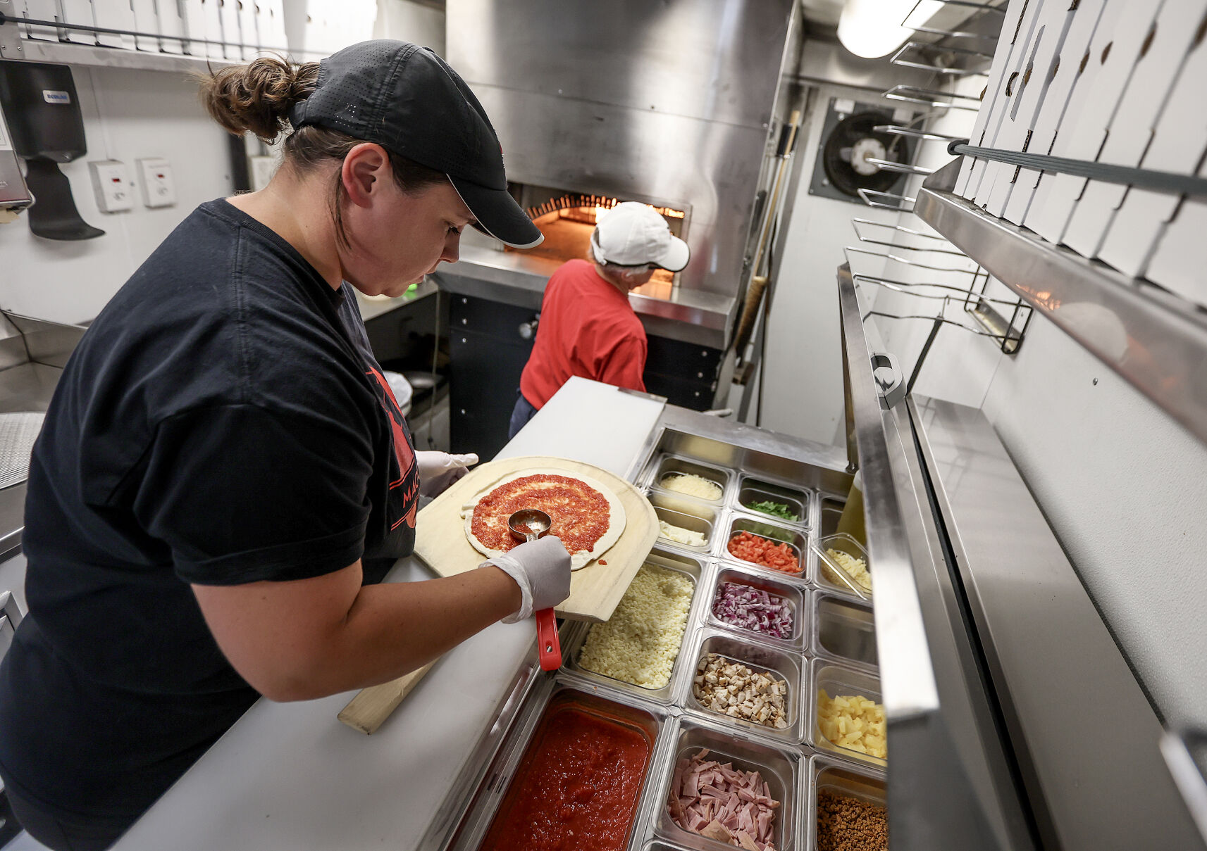 Magoo’s Pizza General Manager Molly Richardson prepares a pizza for a customer at Washington Square in Dubuque.    PHOTO CREDIT: Dave Kettering Telegraph Herald