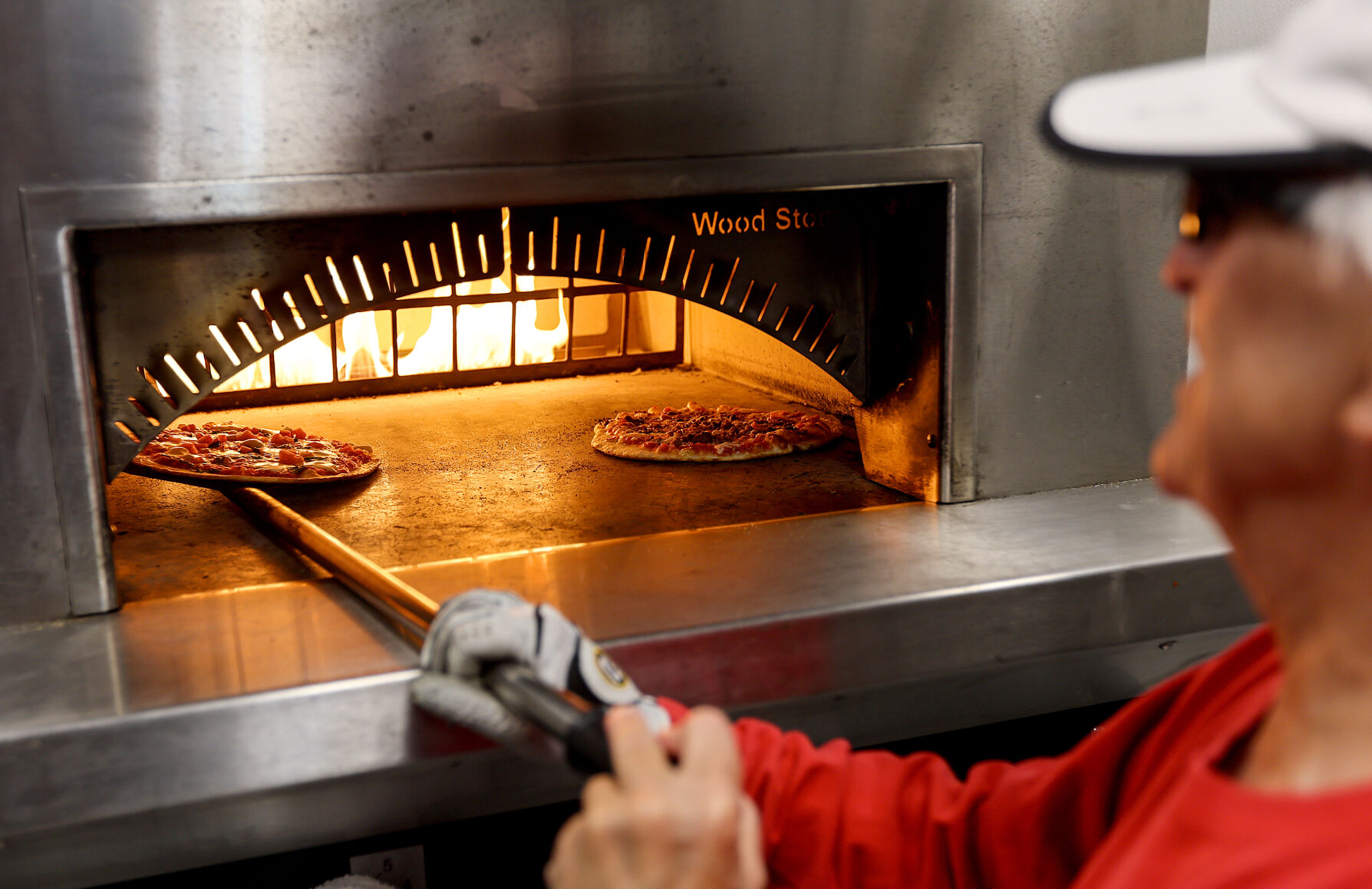 Saks checks on a pizza while serving at Washington Square.    PHOTO CREDIT: Dave Kettering Telegraph Herald