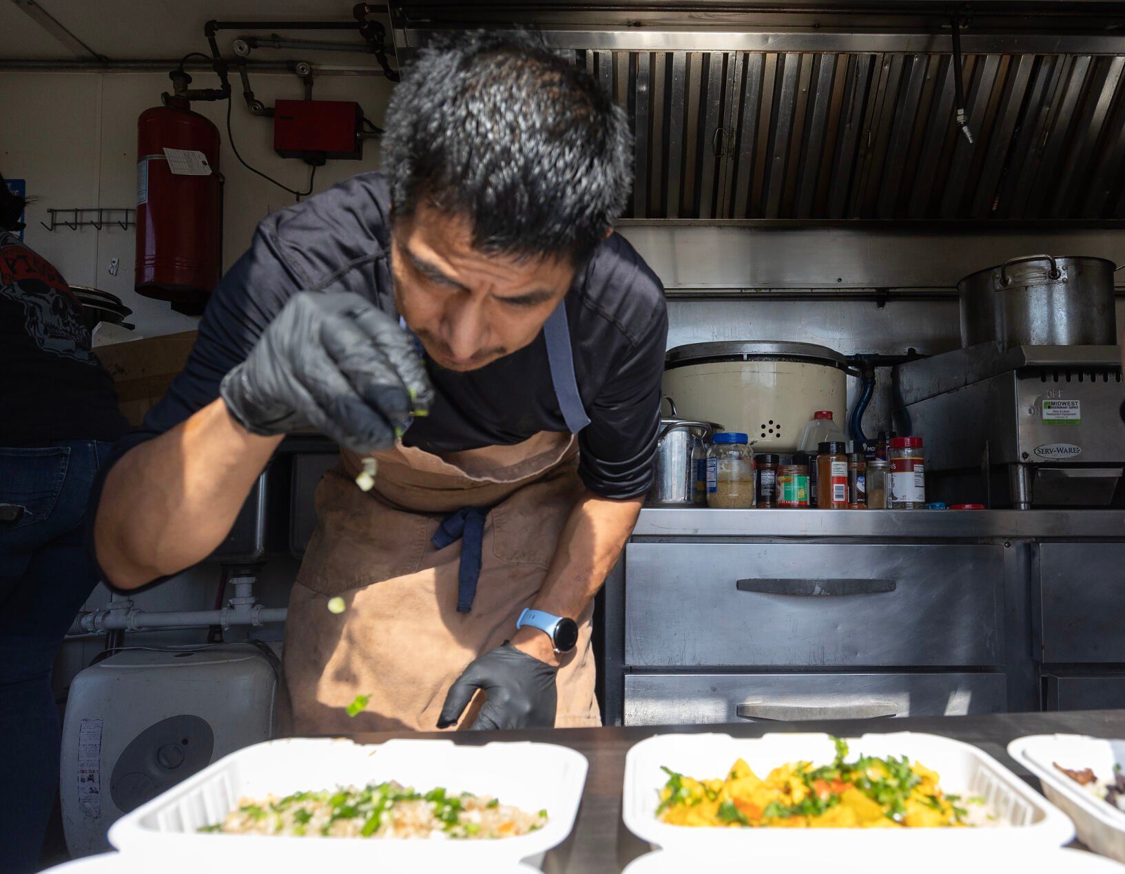 Owner Tomas Weber prepares a meal at The Rice is Nice food truck while parked in Cuba City, Wis., on Saturday.    PHOTO CREDIT: Stephen Gassman