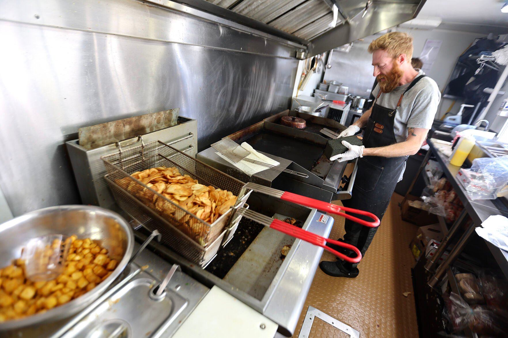 Adam Reisen works in the kitchen for the Hangry’er Hobo food truck last week.    PHOTO CREDIT: Dave Kettering