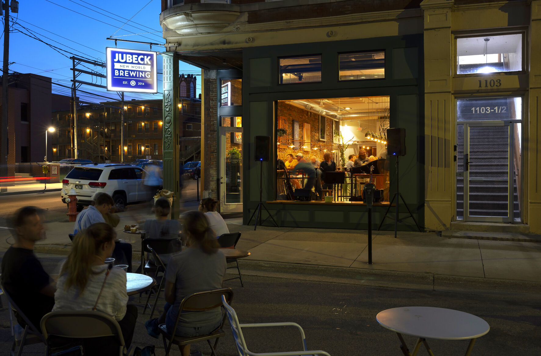 A crowd sits on Iowa Street listening to open mic night at Jubeck New World Brewing.    PHOTO CREDIT: File photo