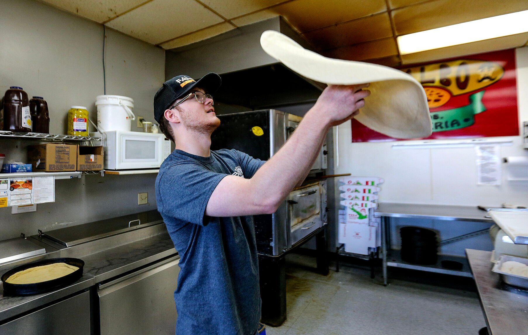 Aidan Brown, 19, the new owner of Falbo Bros. Pizzeria in Dubuque, makes a pizza dough on Monday.    PHOTO CREDIT: Dave Kettering