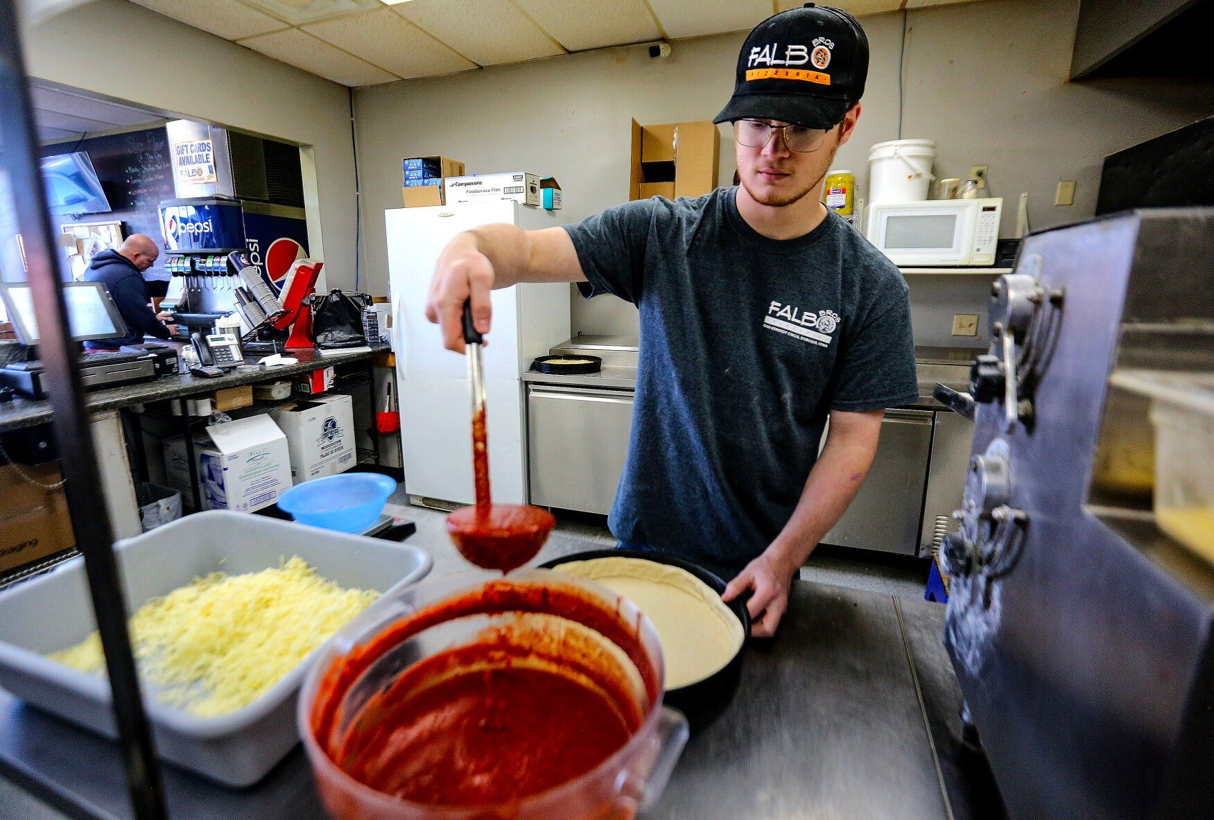 Aidan Brown, 19, makes a pizza on Monday. Brown is the new owner of Falbo Bros. Pizzeria in Dubuque.    PHOTO CREDIT: Dave Kettering