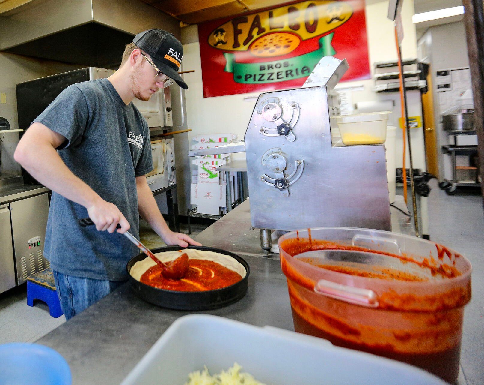 Aidan Brown, 19, makes a pizza on Monday. Brown is the new owner of Falbo Bros. Pizzeria in Dubuque.    PHOTO CREDIT: Dave Kettering