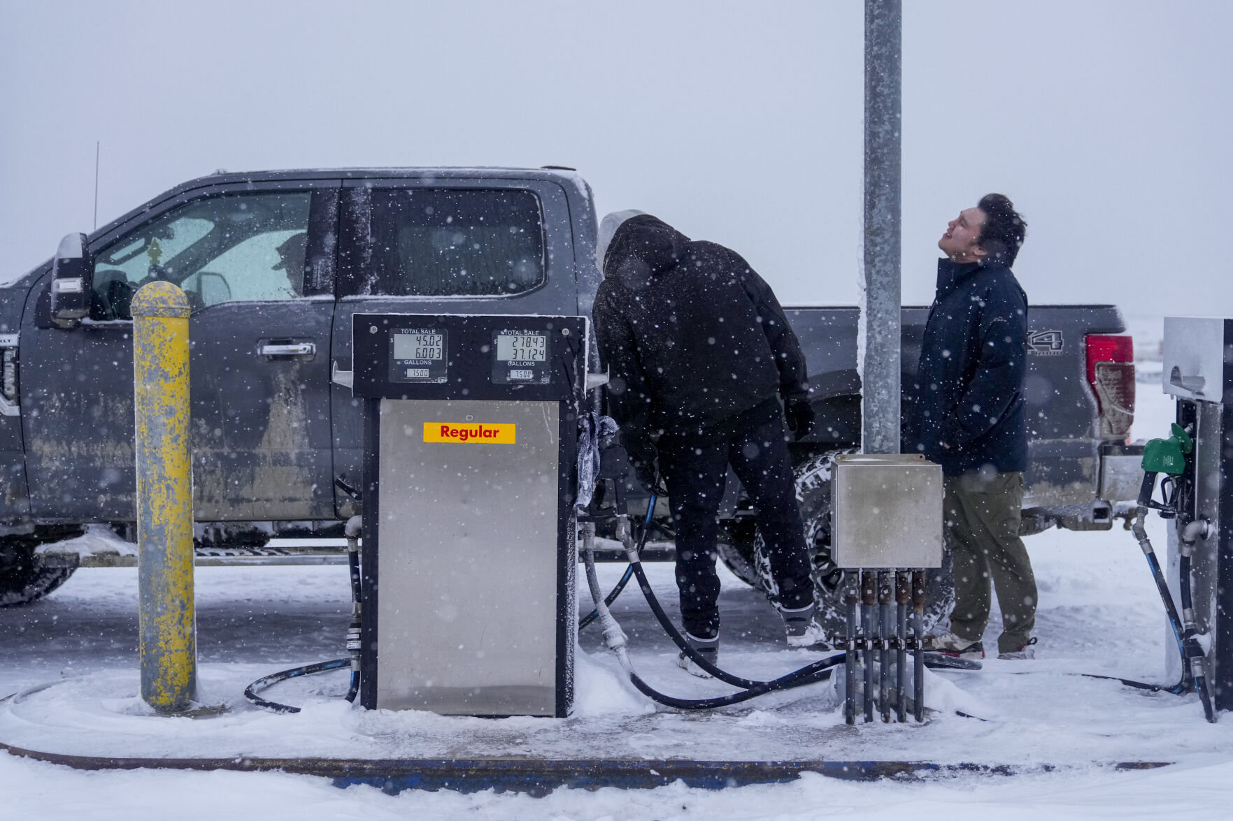 <p>FILE- Edwin Solomon, 18, at right, stands in the wind and snow while filling up a truck with regular gas at a price of $7.50 a gallon, Wednesday, Oct. 16, 2024, in Kaktovik, Alaska. (AP Photo/Lindsey Wasson, File)</p>   PHOTO CREDIT: Lindsey Wasson - staff, ASSOCIATED PRESS