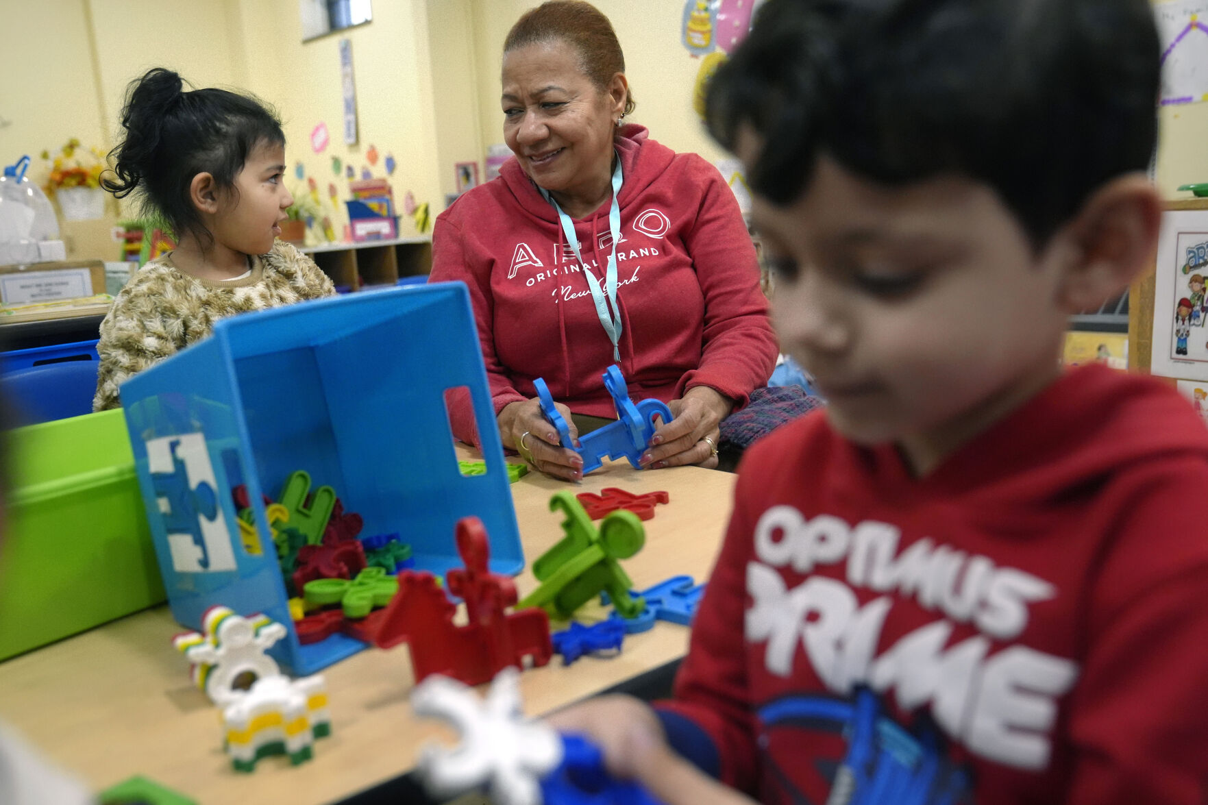 <p>Volunteer Evangelista Baez, 72, of Providence, R.I., center, supervises three-year-olds Scarlett Mendoza, left, and Gabriel Kubbe, right, in an early childcare program at Federal Hill House, Tuesday, Nov. 12, 2024, in Providence, R.I. (AP Photo/Steven Senne)</p>   PHOTO CREDIT: Steven Senne 