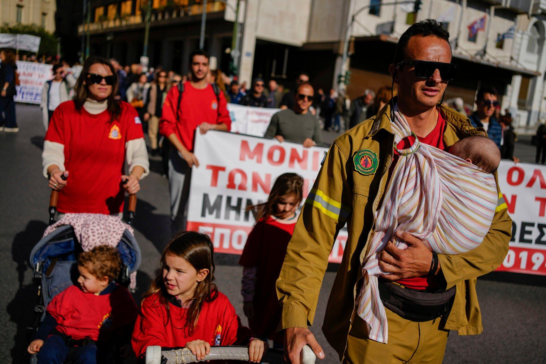 <p>Seasonal firefighter Dimitris Tsolakoudis protests with his four kids and his wife, left, during a nationwide general strike organized by private and public sector unions demanding for better wages, in Athens, Greece, Wednesday, Nov. 20, 2024. (AP Photo/Thanassis Stavrakis)</p>   PHOTO CREDIT: Thanassis Stavrakis - staff, ASSOCIATED PRESS