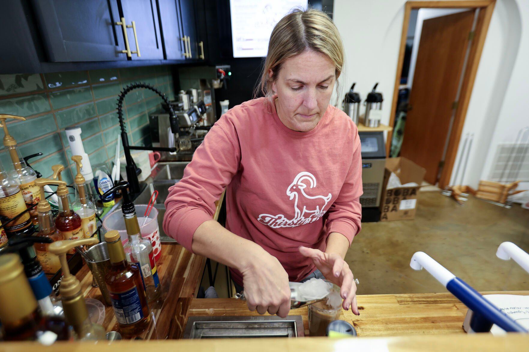 Jayme Lammers, owner of the Thirsty Goat, prepares drinks for a customer at the Farley, Iowa, business on Friday.    PHOTO CREDIT: Dave Kettering