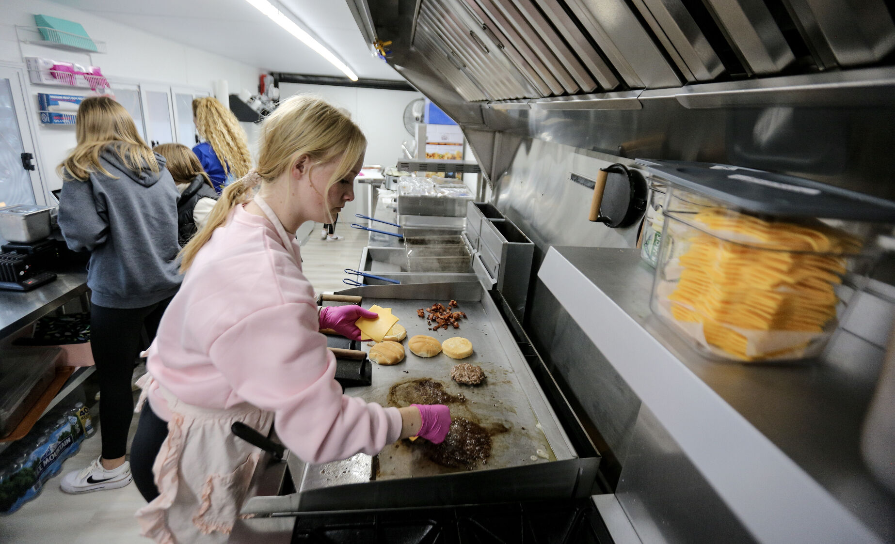 Emma Whitmore works the grill inside the truck.    PHOTO CREDIT: Dave Kettering