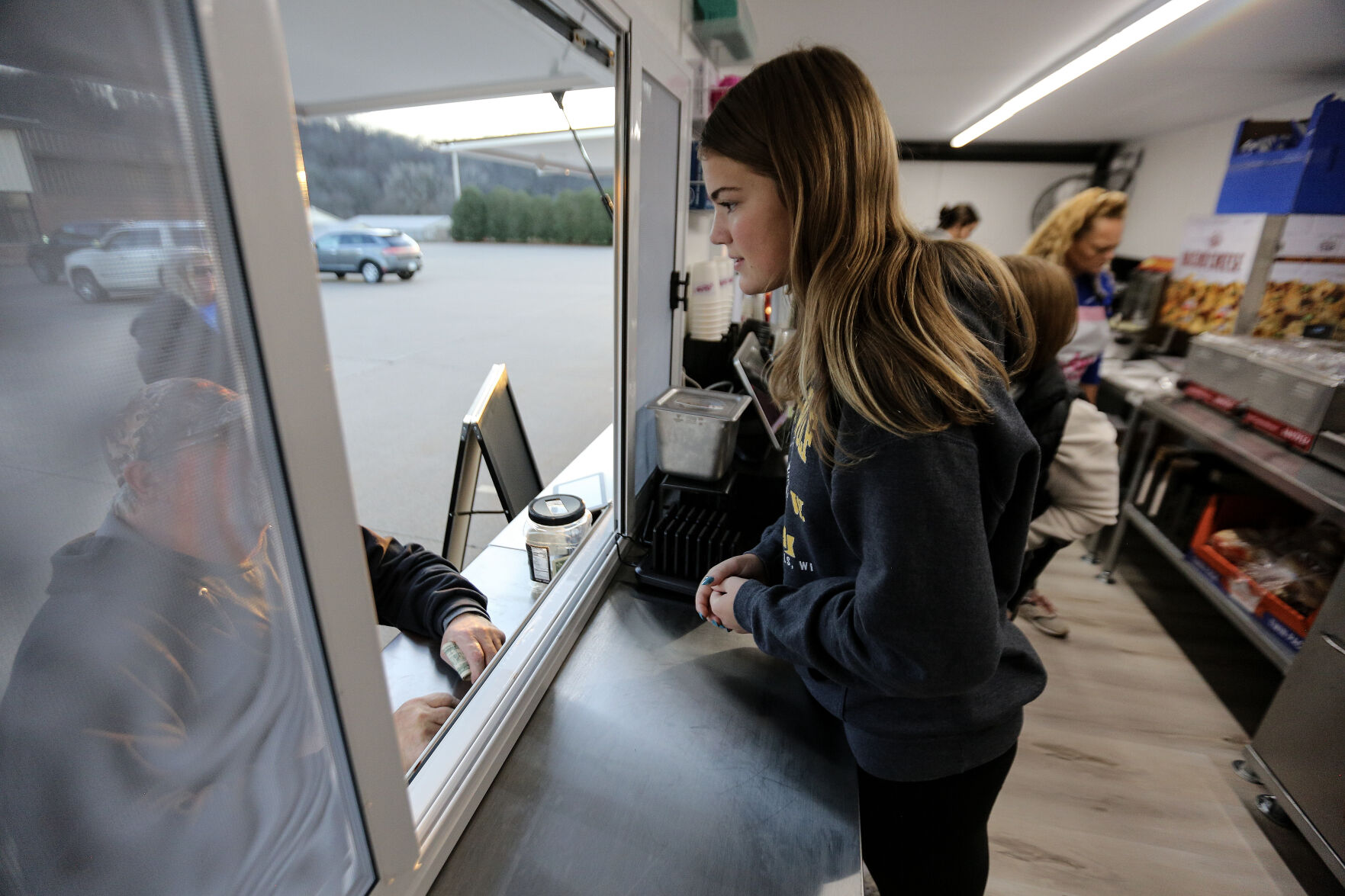 Izzy Tott works the window inside Mickey’s Kitchen food truck.    PHOTO CREDIT: Dave Kettering