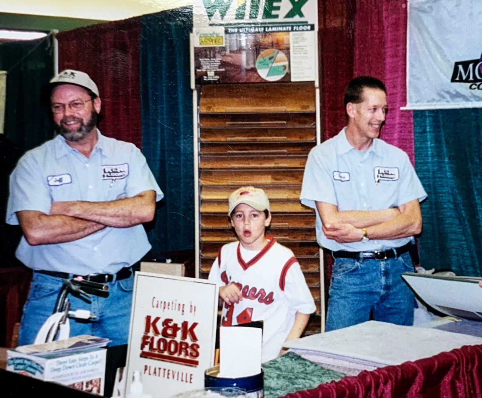 Michael Kliebenstein (center) is seen at a home show with his dad, Jeff (left), and former K&K Floors employee Craig Meyer. Michael began helping his dad at the family flooring business when he was a kid and began working for the firm full time in 2011.    PHOTO CREDIT: Contributed