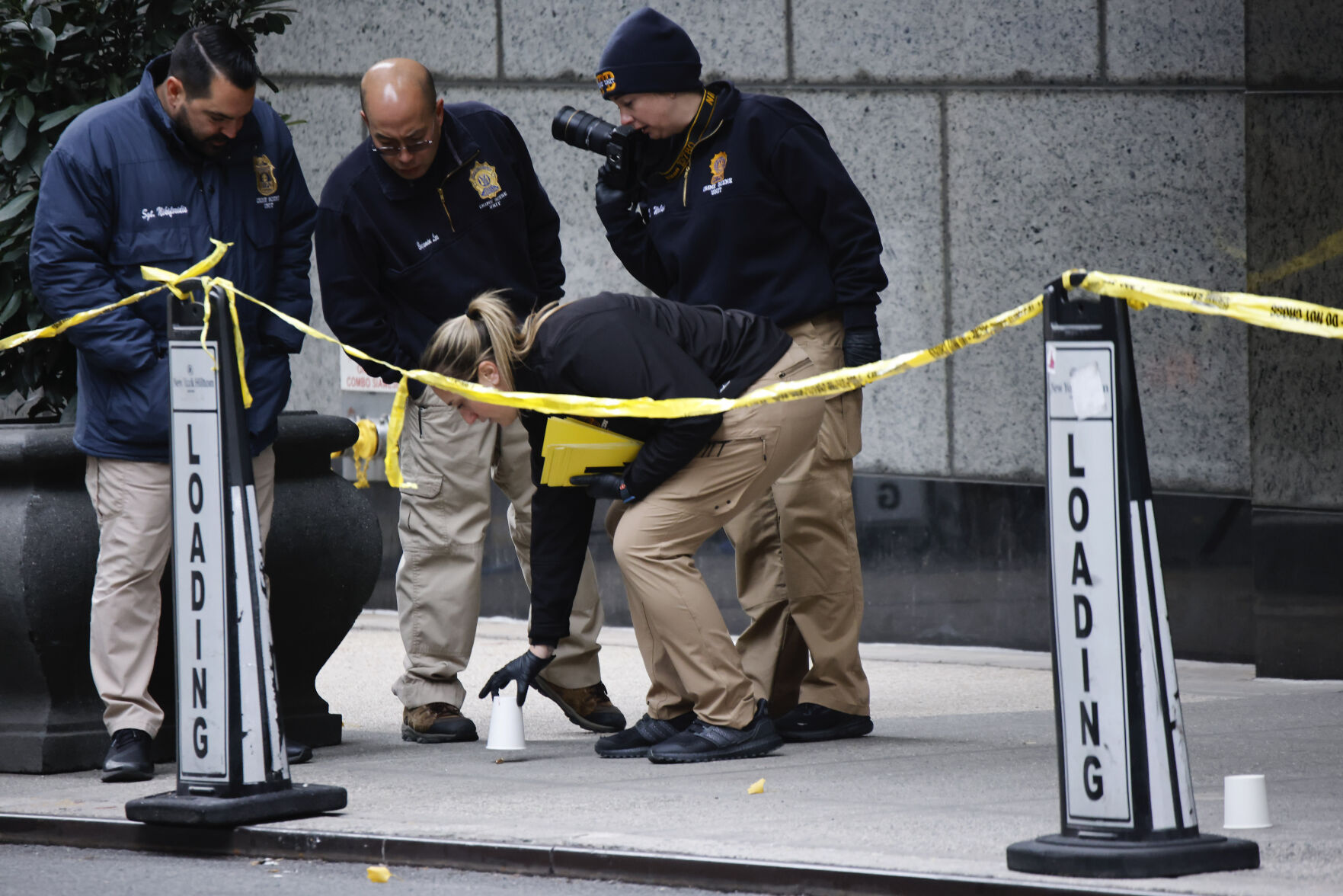 <p>Members of the New York police crime scene unit pick up cups marking the spots where bullets lie as they investigate the scene outside the Hilton Hotel in midtown Manhattan where Brian Thompson, the CEO of UnitedHealthcare, was fatally shot Wednesday, Dec. 4, 2024, in New York. (AP Photo/Stefan Jeremiah)</p>   PHOTO CREDIT: Stefan Jeremiah - freelancer, ASSOCIATED PRESS