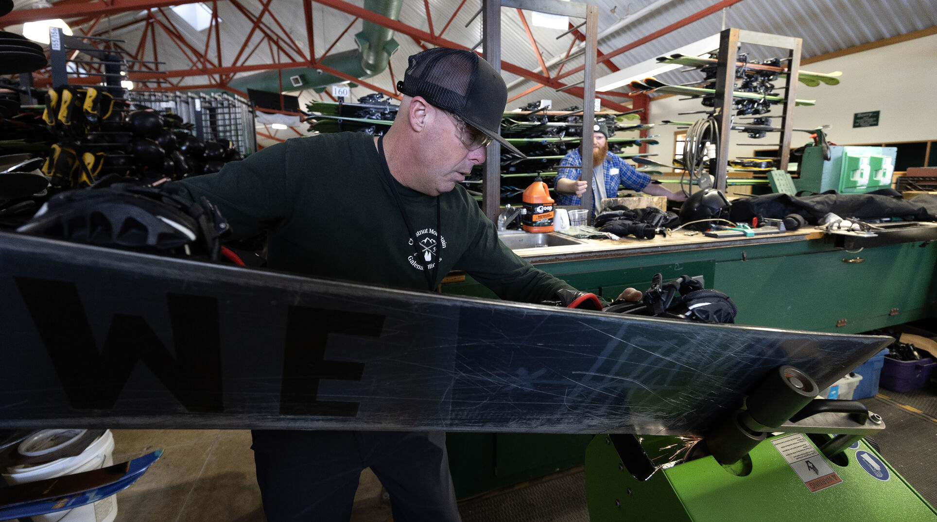 Phil Schuler sharpens a snowboard at Chestnut Mountain.    PHOTO CREDIT: Gassman