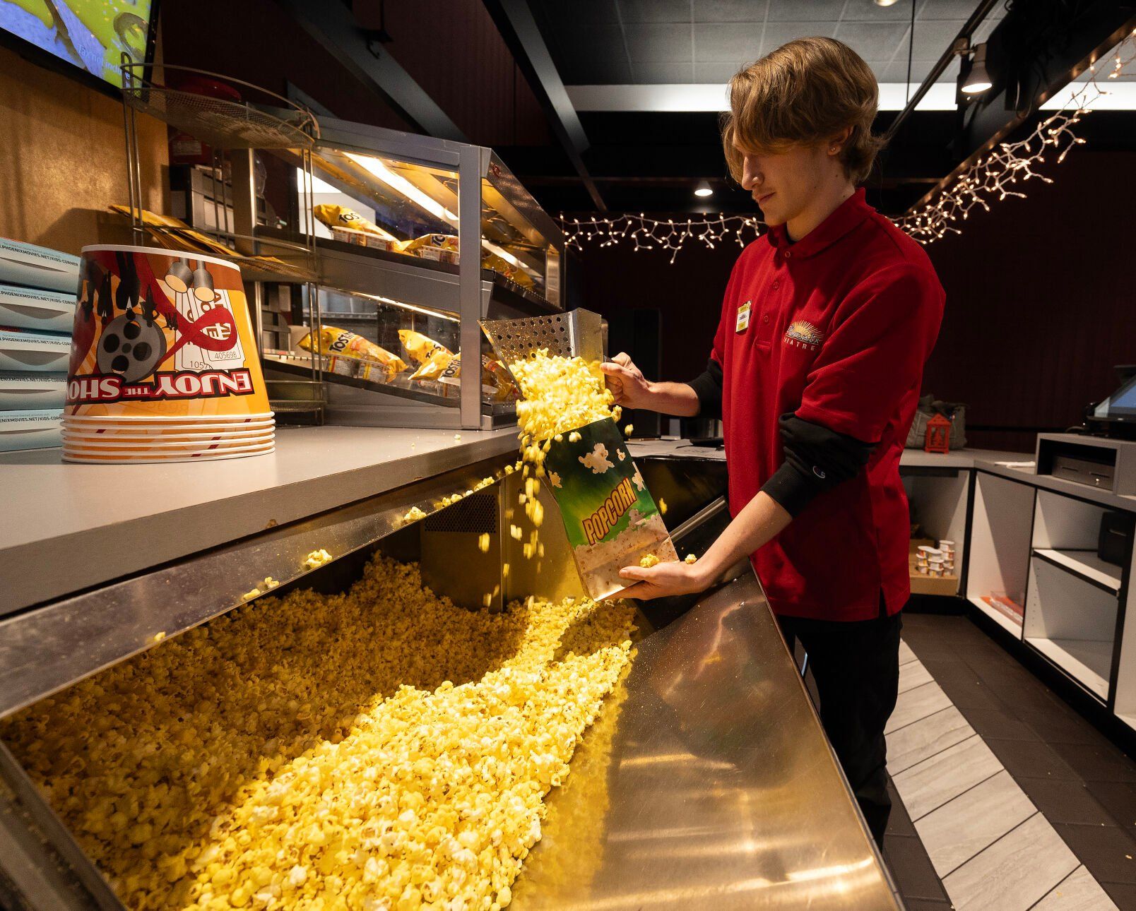 Phoenix Theatres employee Ethan Campbell scoops popcorn for a customer at the Dubuque movie theater on Tuesday.    PHOTO CREDIT: Stephen Gassman