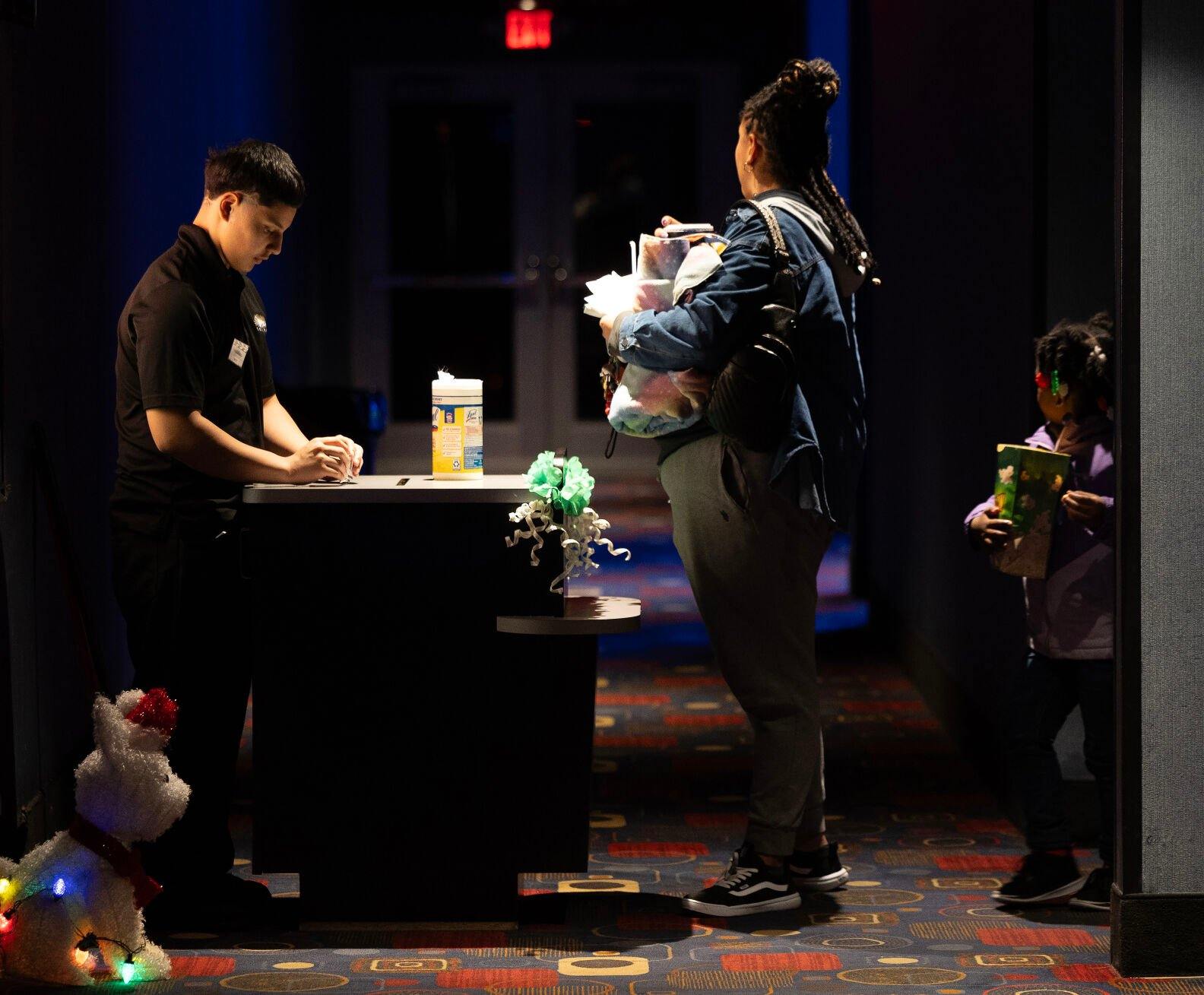 Phoenix Theatres employee Niyo Rowa takes tickets from Tolisa Lafayette at the Dubuque movie theater on Tuesday. Some recent hits have drawn crowds to theaters.    PHOTO CREDIT: Gassman