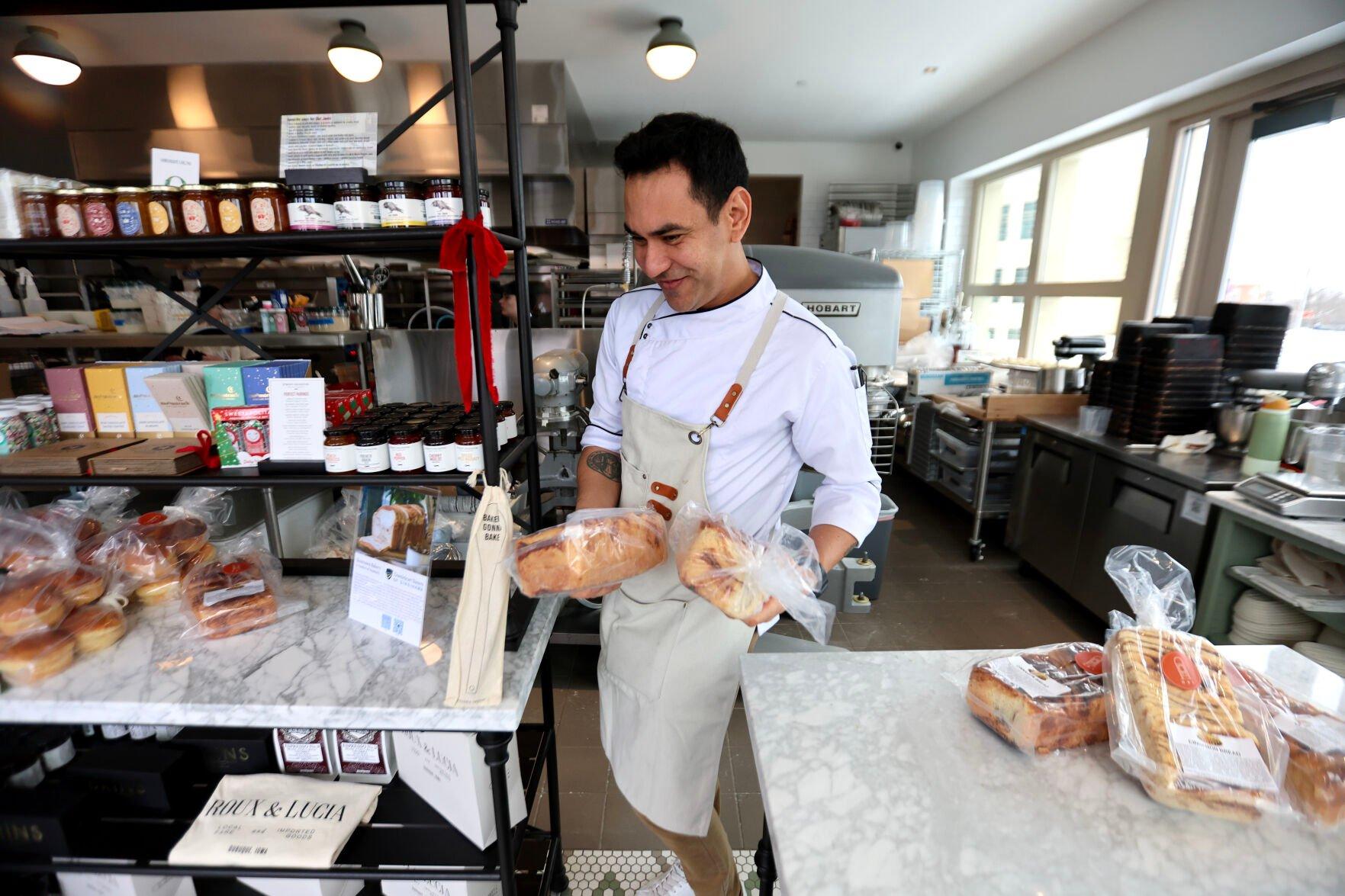 Fernando Escalante stocks the shelves with Sinsinawa cinnamon bread at Roux & Lucia bakery on Friday. The bakery serves a variety of fresh breads and pastries.    PHOTO CREDIT: Dave Kettering